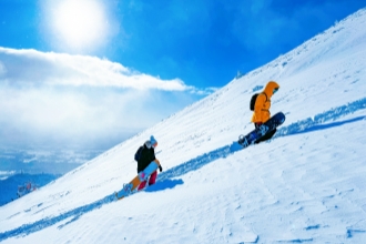 Snowboarders climb a snowy slope, hokkaido